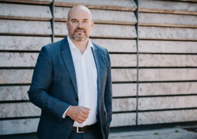 Businessportrait eines Geschäftsführers im Sakko vor einer Holzfassade