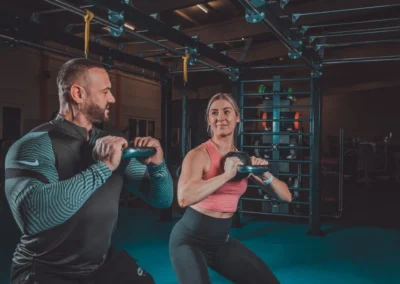 Personaltrainer beim Kettlebell-Training mit Kundin im Studio