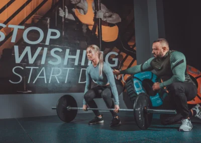 Personaltrainer korrigiert die Technik beim Kreuzheben