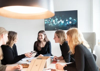 Teamfoto bei LESON: Mitarbeiterinnen im Gespräch am Besprechungstisch